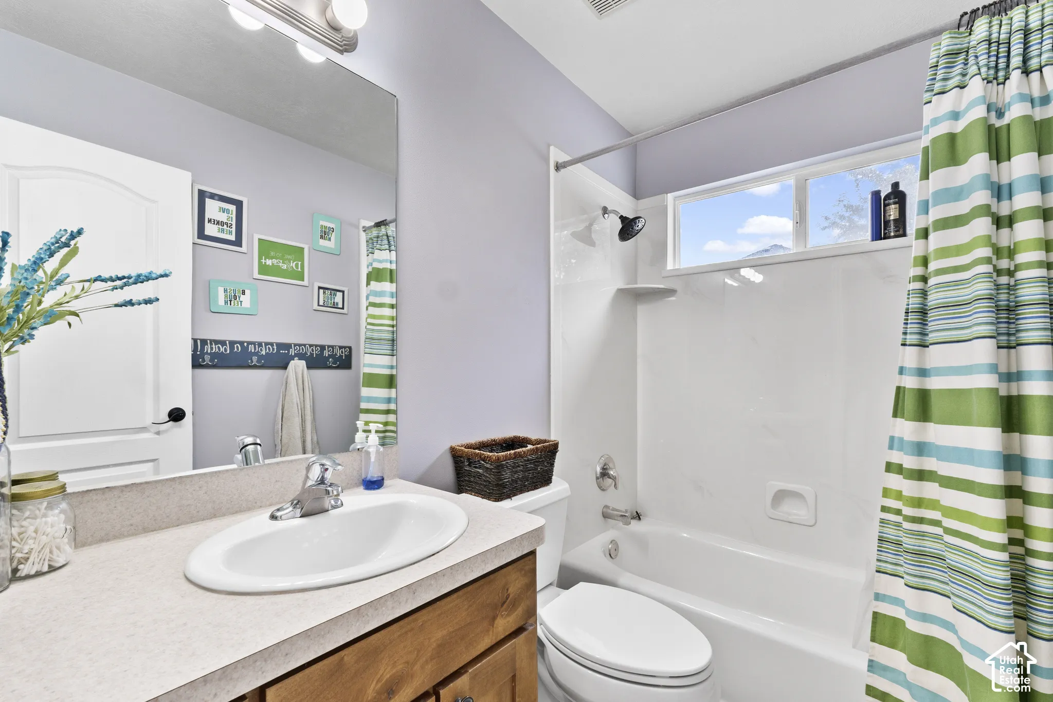 Bathroom with a single vanity, undermount sink, and a combination tub/shower with a window