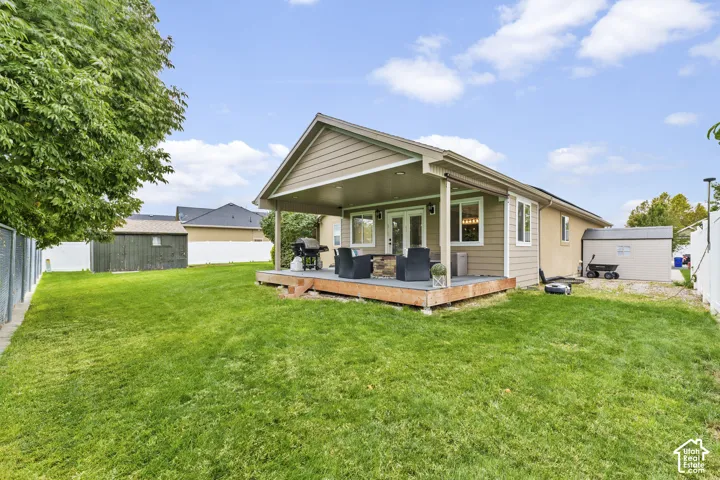 Expansive backyard featuring a covered patio, wood-finish decking, and a privacy fence