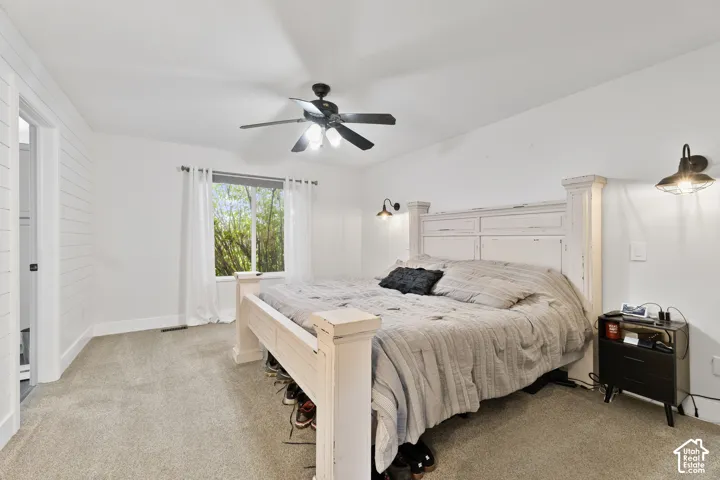 Master Bedroom featuring a ceiling fan with integrated lighting, a window with outdoor scenery, and wall-mounted sconces
