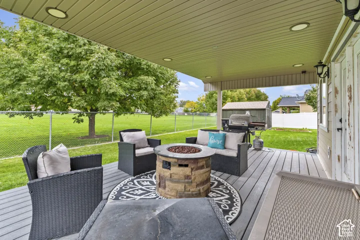 Covered composite deck featuring recessed lighting and a stone-clad fire pit