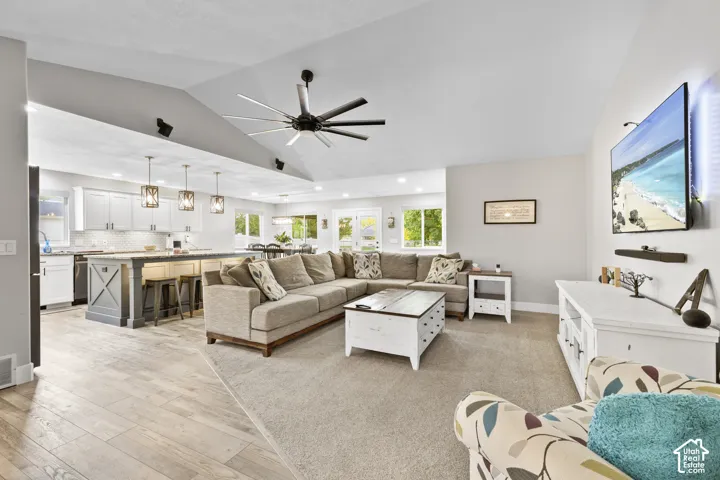 Vaulted ceiling, ceiling fan, wood-finish flooring, recessed lighting, and kitchen island with pendant lighting