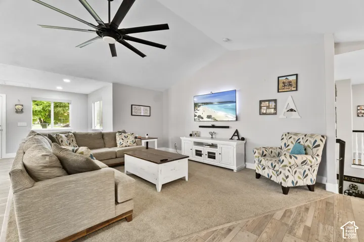 Vaulted ceiling with a multi-blade ceiling fan, recessed lighting, and large window with exterior greenery