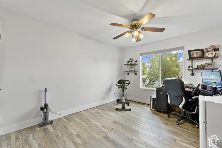 Wood-finish flooring, ceiling fan with integrated lighting, window with exterior scenery, and white wall finishes. Also has a closet.