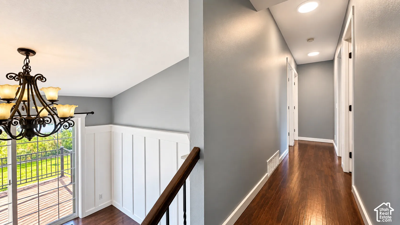 Hardwood flooring, recessed lighting, white board and batten wall paneling, and an ornate chandelier