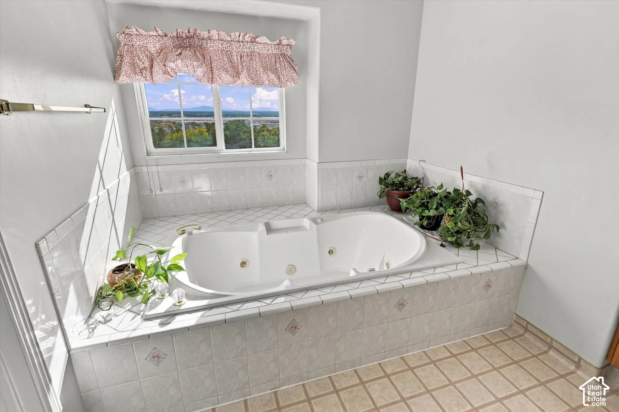 Built-in jetted tub surrounded by white tile, with a window offering a distant landscape. En-suite.