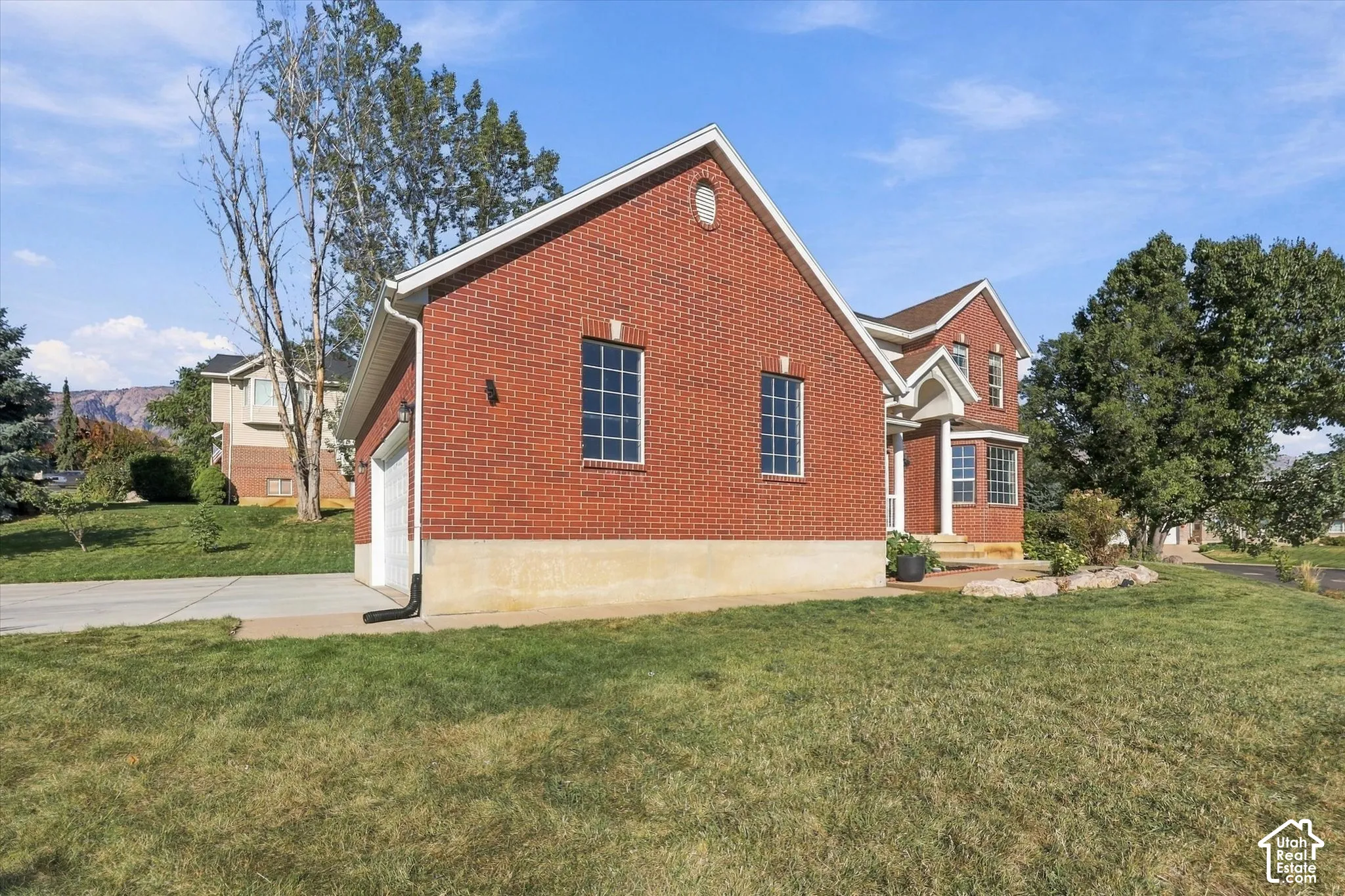 Brick exterior with white trim, a concrete driveway, an attached garage, and a landscaped rock garden