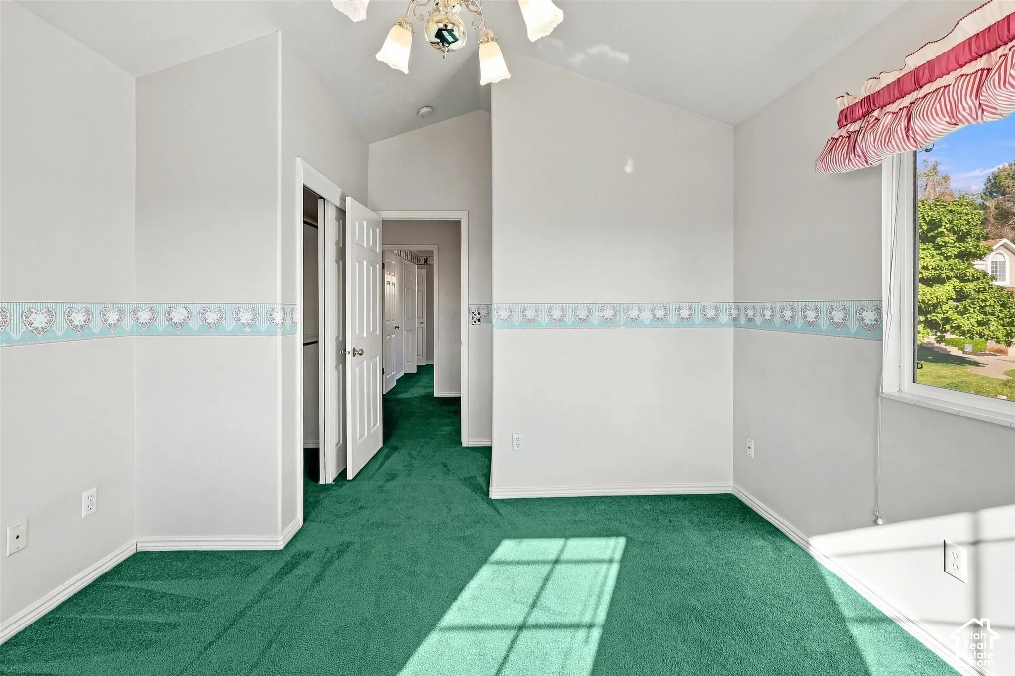 Vaulted ceiling, wall-to-wall carpeting, white interior doors, and a decorative ceiling light fixture