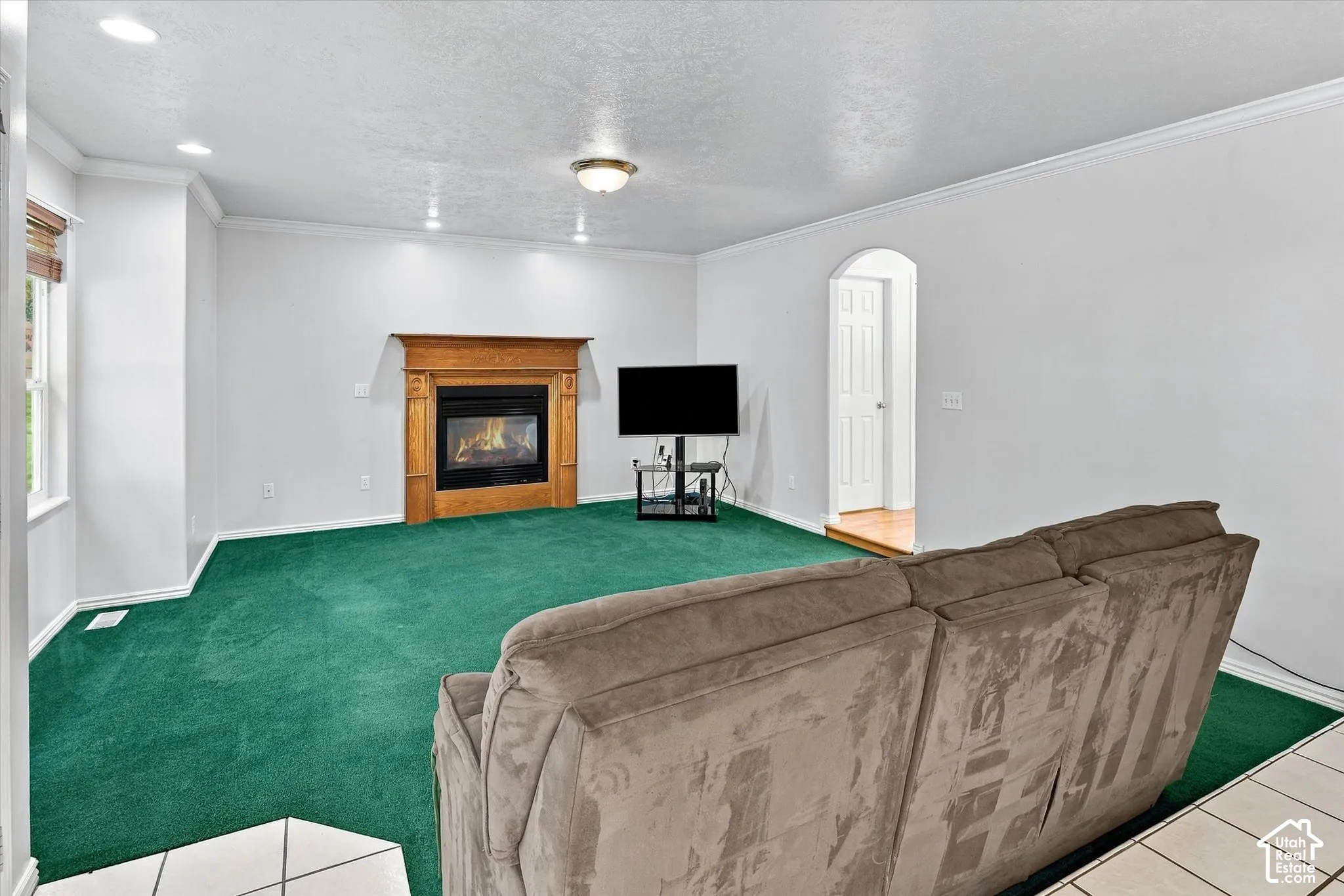 Living area featuring a gas fireplace with a wood mantle, recessed lighting, and crown molding