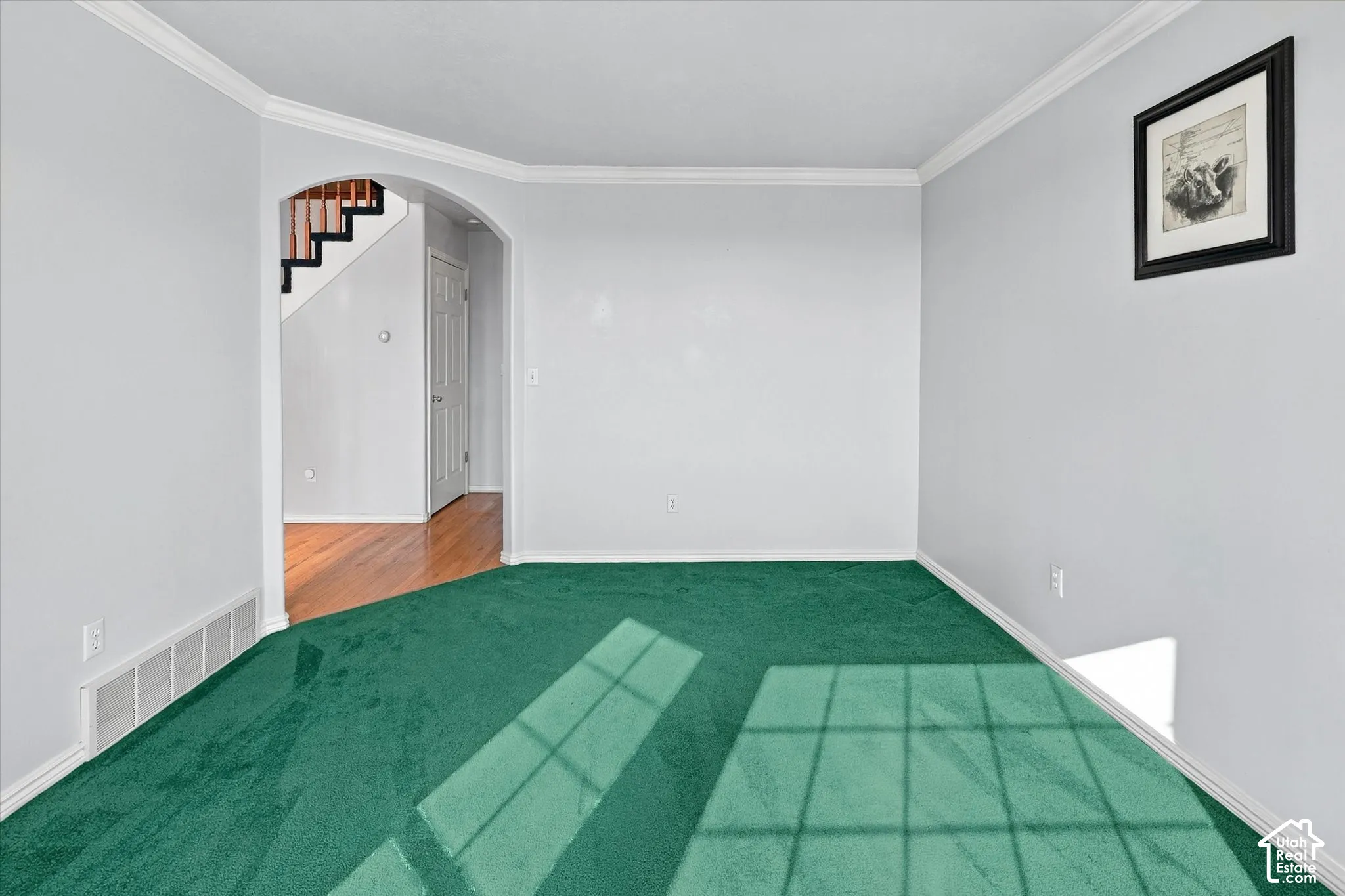 Archway entry to a space with wood-finish flooring and staircase