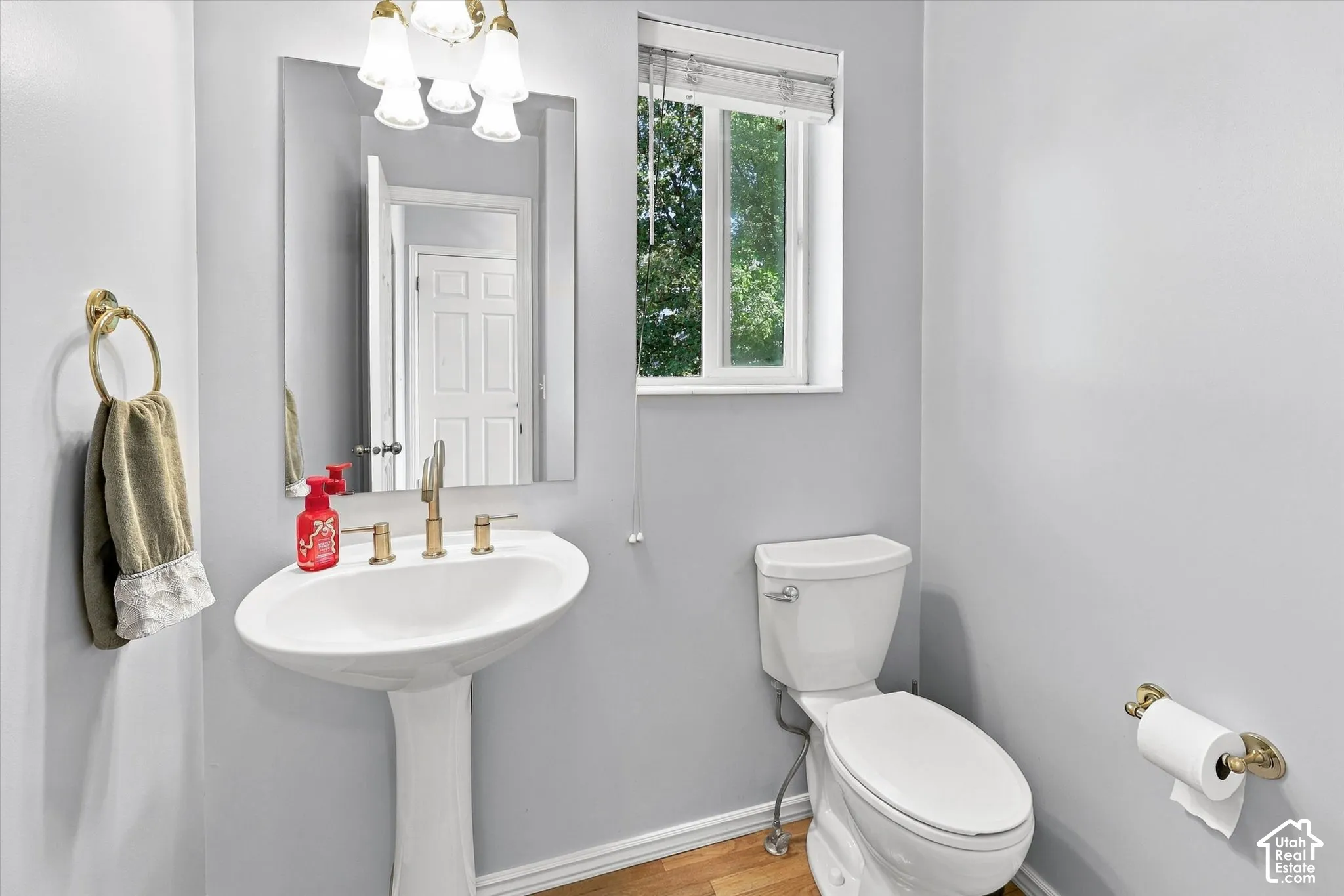 Pedestal sink with brass-finish faucet, rectangular mirror, and wall-mounted light fixture