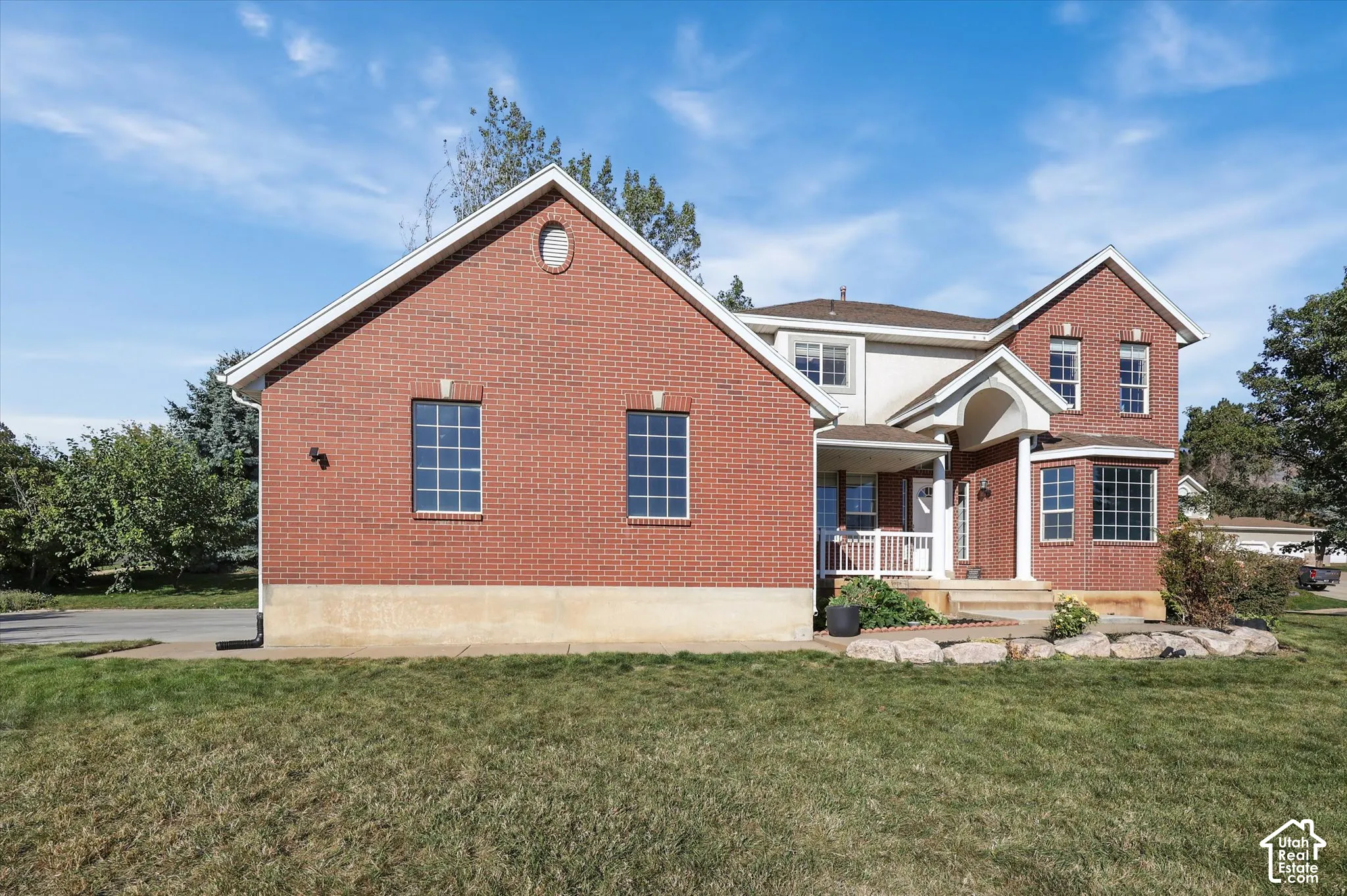Brick exterior with a gabled roofline, multiple windows, covered porch, and a bay window
