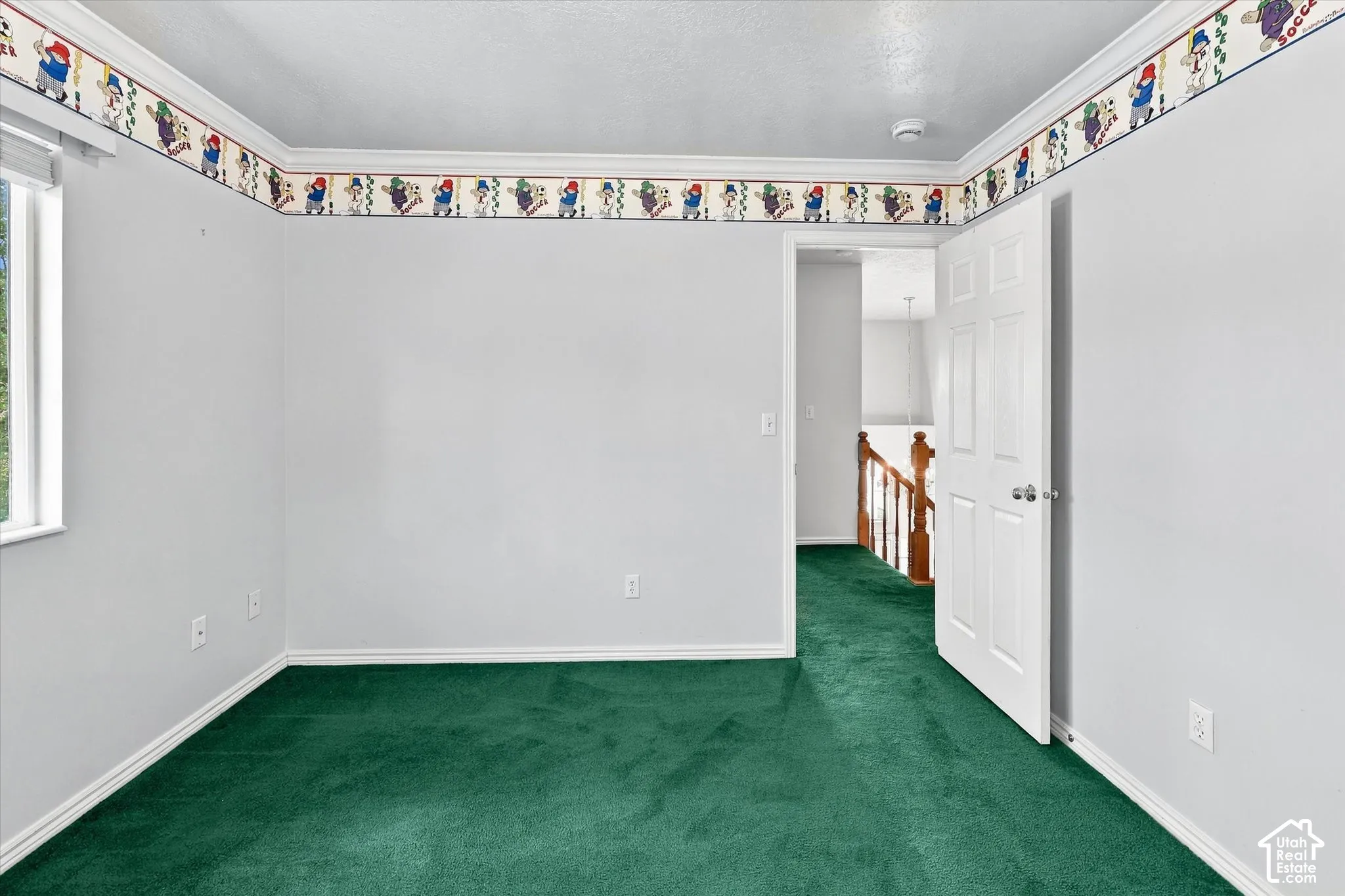Window with white trim, green carpet, white painted walls, white door, and wooden handrail