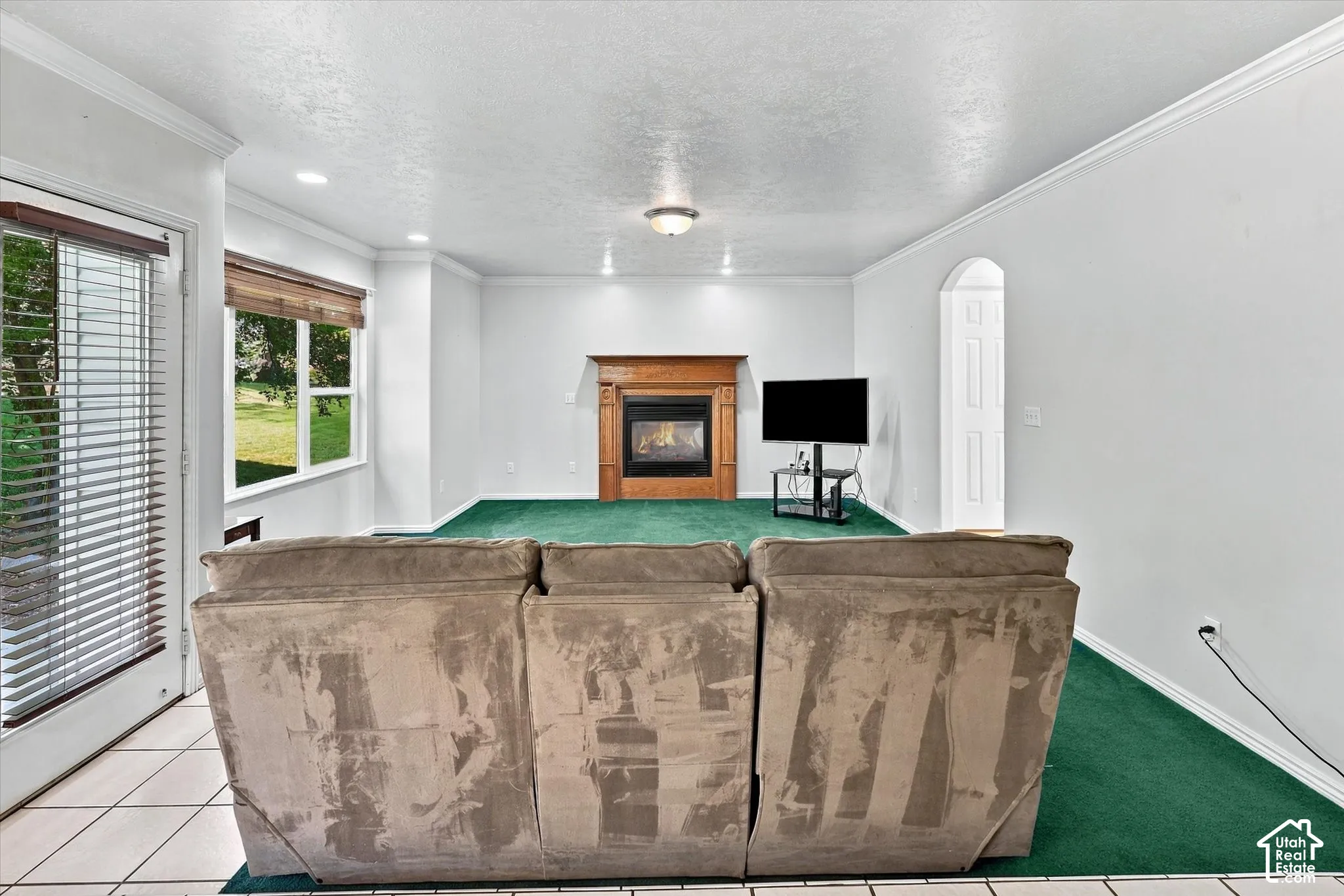 Living area featuring a fireplace with a wood surround, large window, door with blinds, and recessed lighting
