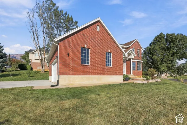 Brick exterior with white trim, a concrete driveway, an attached garage, and a landscaped rock garden