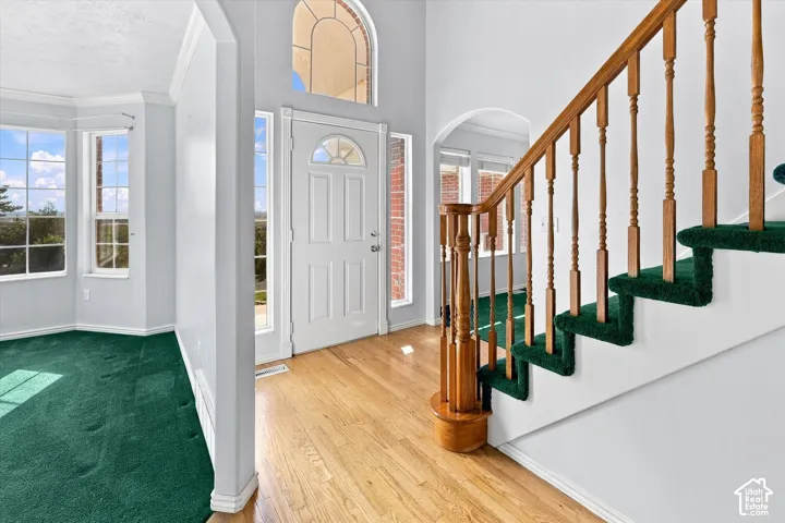 Entryway with wood-finish flooring, a decorative arched transom window, and a staircase featuring wood railings
