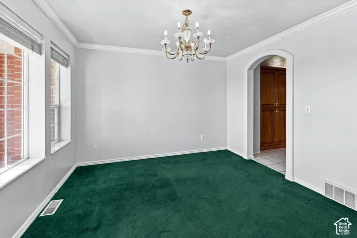 Room featuring wall-to-wall carpeting, crown molding, and an arched doorway