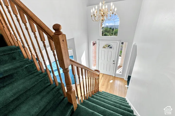 Two-story foyer with hardwood flooring, a white front door featuring a transom window, and an arched entryway