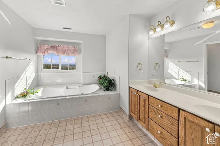 En-suite bathroom with Amazing View. Integrated soaking tub with tiled surround, dual vanity with wood cabinetry, expansive countertop, and large wall-mounted mirror