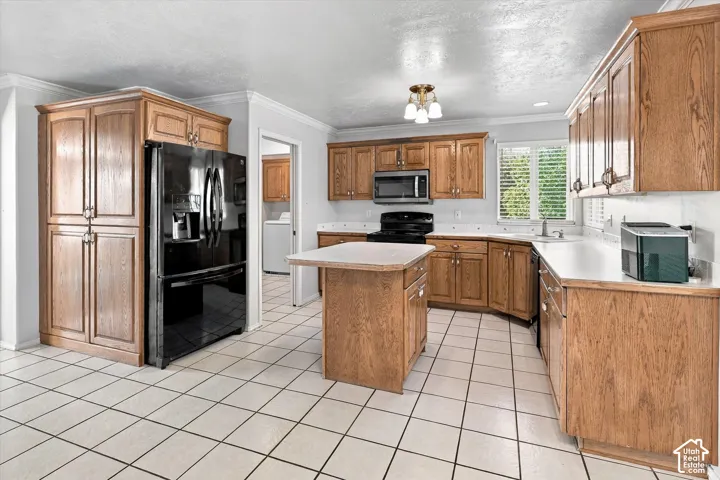 Kitchen featuring light wood cabinetry, white countertops, tile flooring, and a central island