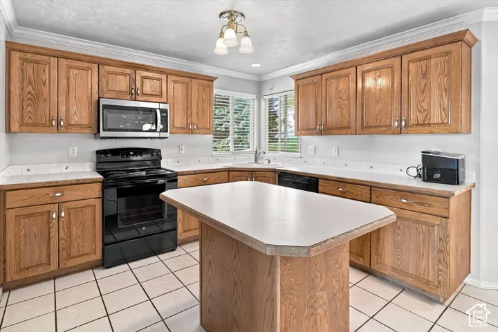 Kitchen featuring wood cabinetry, white countertops, tile flooring, a center island, and stainless steel appliances