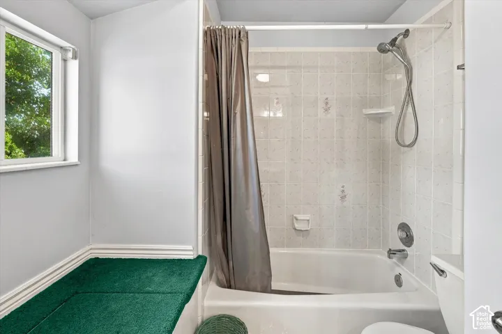 Bathtub and shower combination with tiled surround, and a window providing natural light
