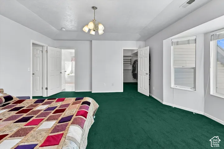 Room with neutral wall paint, green carpet, and a multi-light chandelier