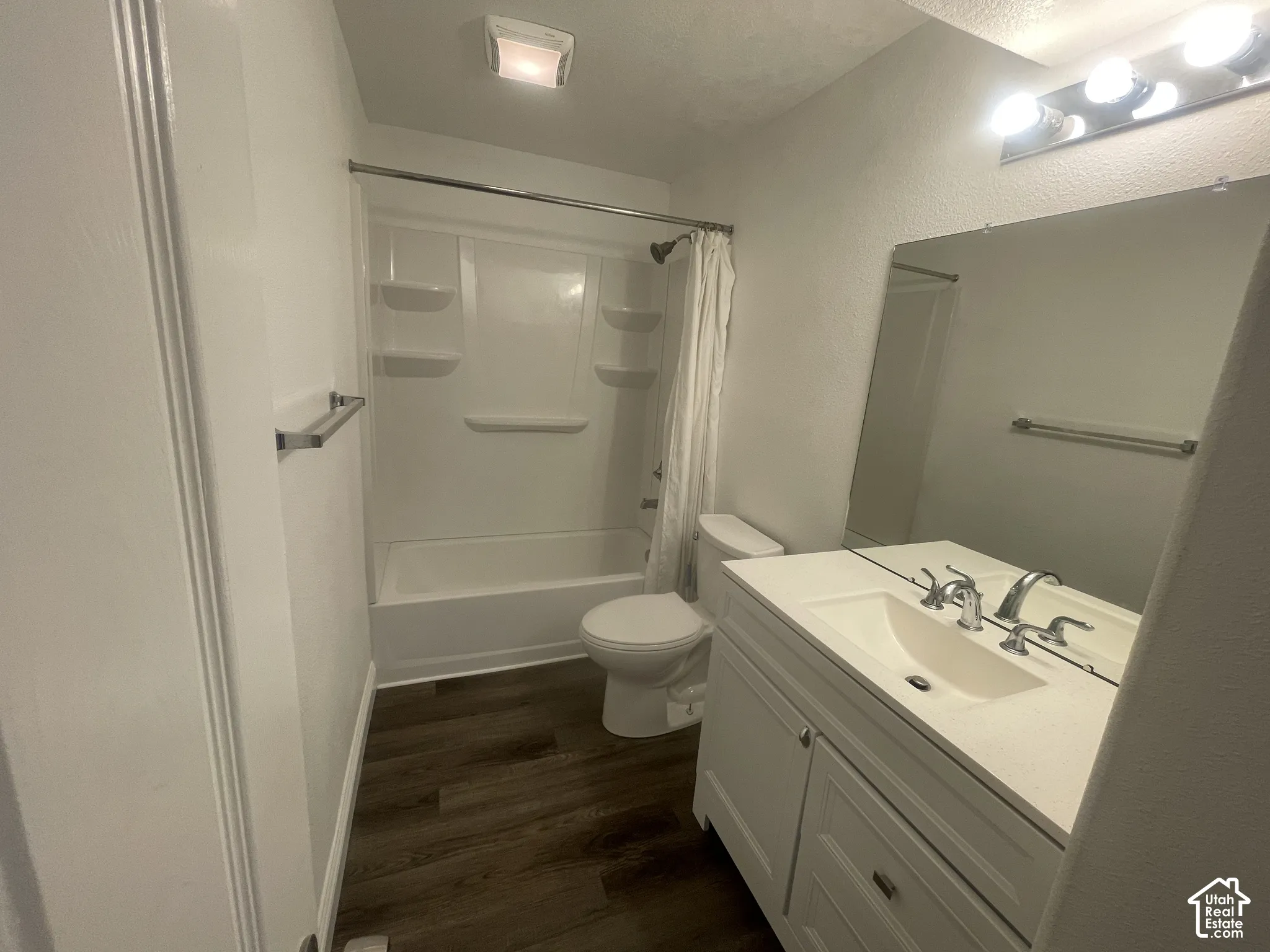 Bathroom featuring a white vanity with integrated sink, chrome faucet, and wood-finish flooring
