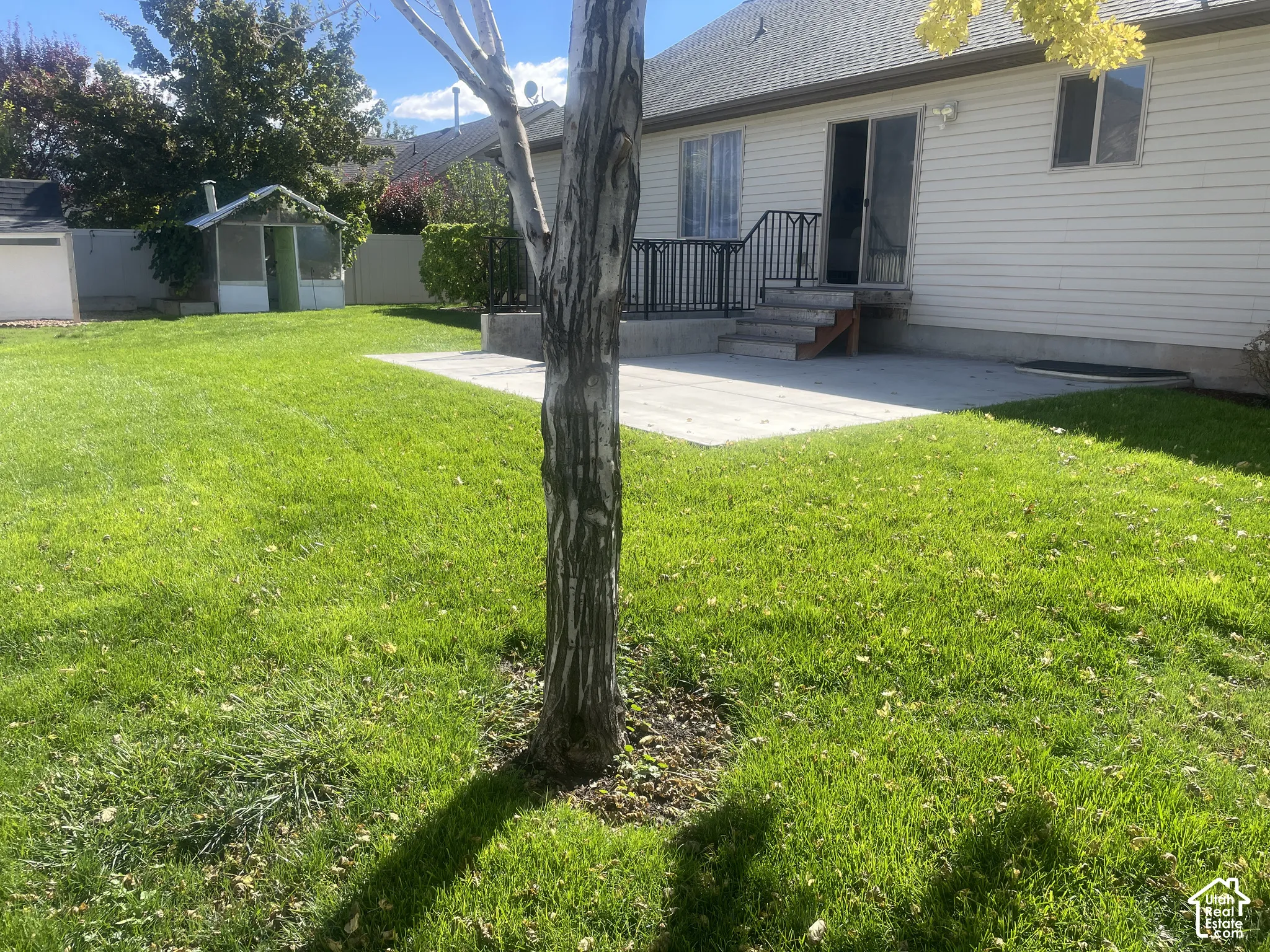Expansive lawn area with a concrete patio and a screened structure