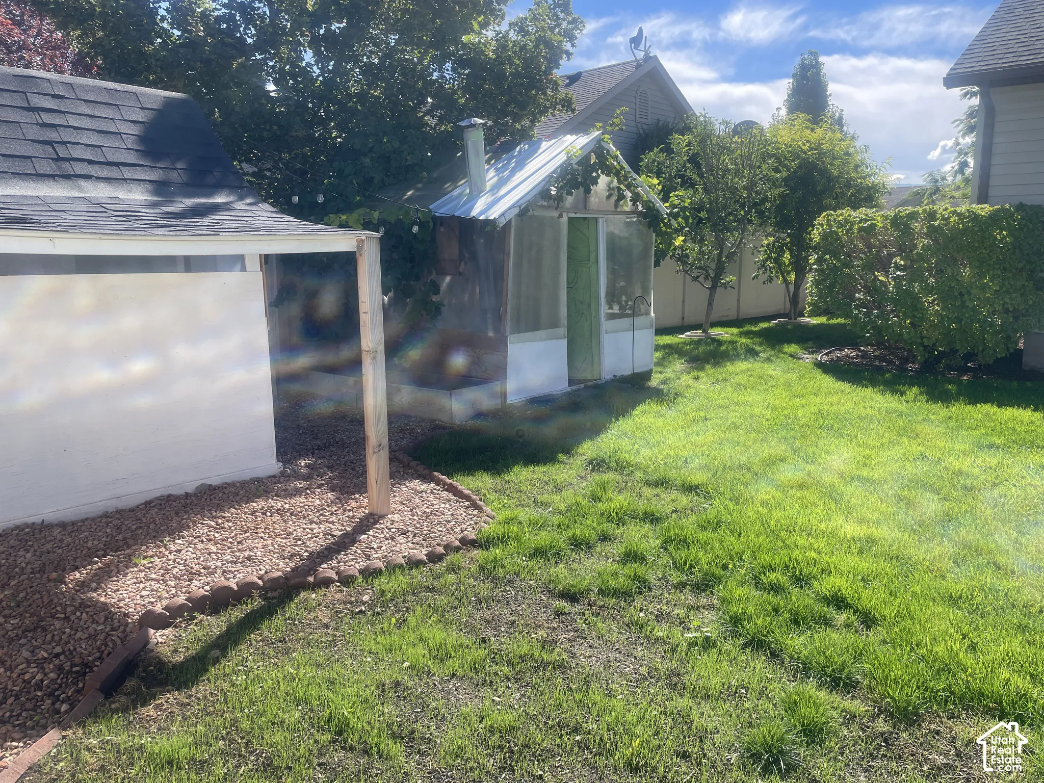 Greenhouse structure, manicured lawn, established landscaping, privacy fencing