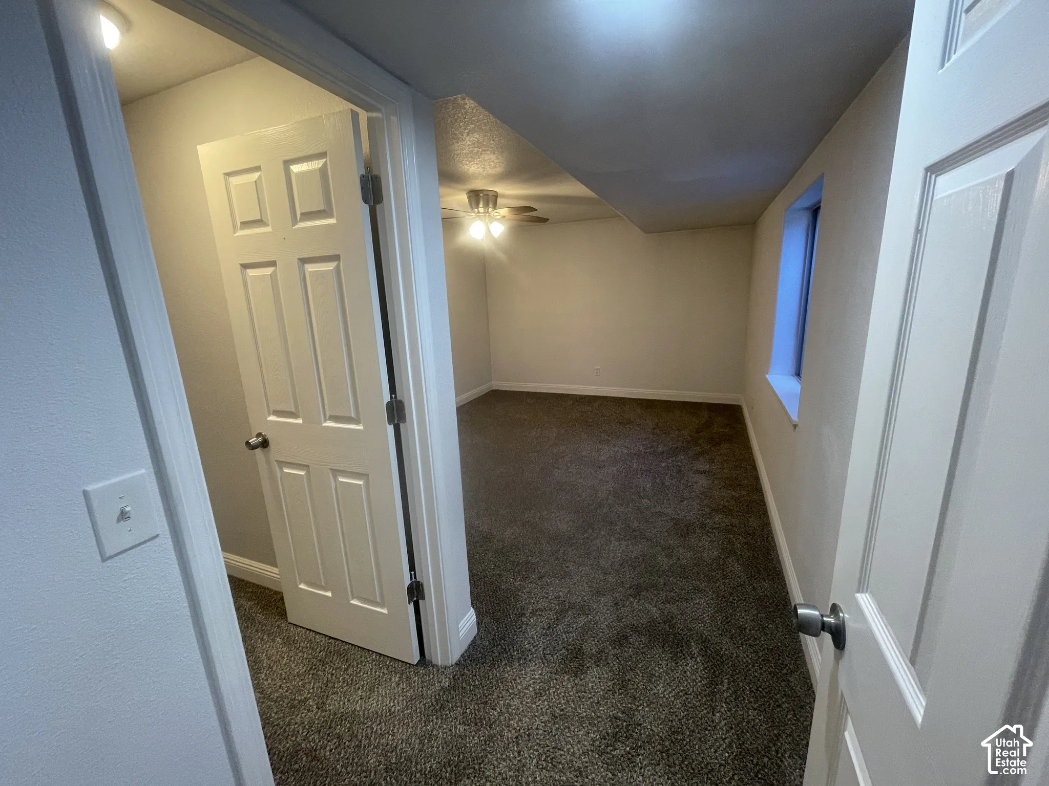 Carpeted flooring, egress window, white trim, and ceiling fan