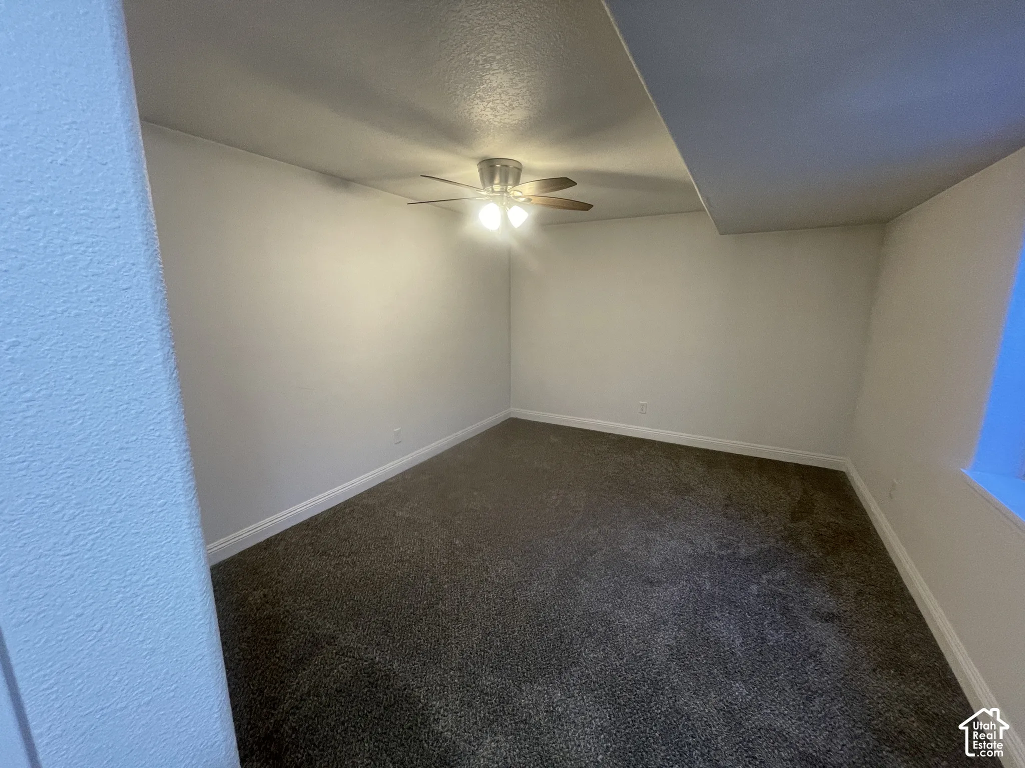 Carpeted flooring, white walls, and a ceiling fan with integrated lighting