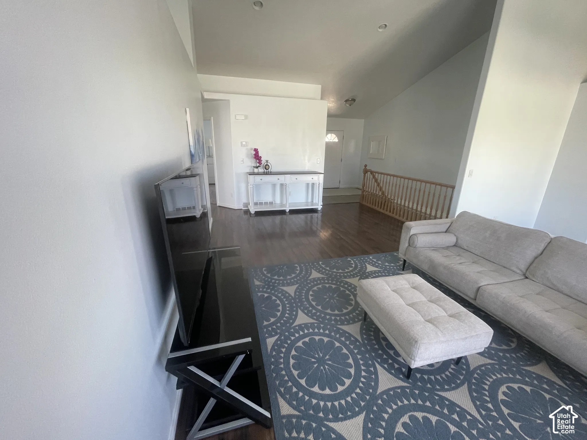 Vaulted ceilings, wood-finish flooring, and white painted walls create an inviting living space