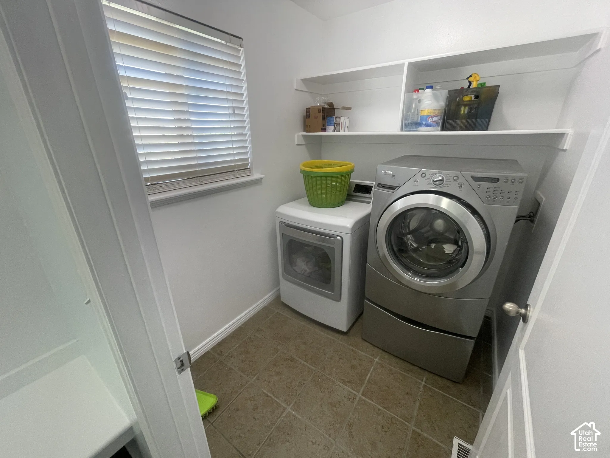 Window with blinds, wall-mounted shelving, and tiled flooring