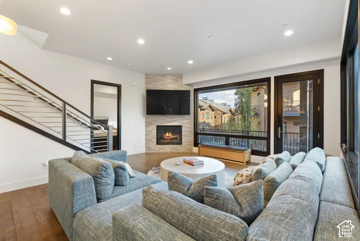 Open-concept living area featuring a modern fireplace with a textured surround, large picture windows, and wood-finish flooring
