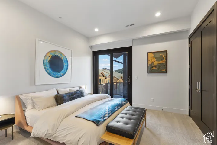 Recessed lighting, light-colored carpeting, dark wood-finish interior doors, and a sliding glass door leading to a private outdoor balcony