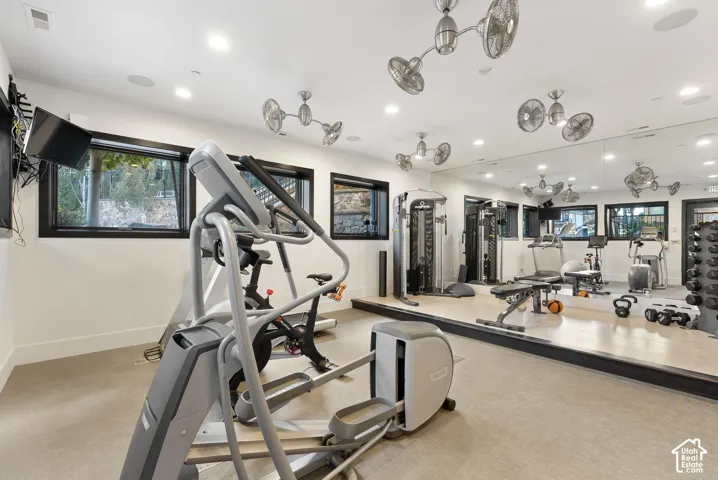 Dedicated exercise room featuring full-wall mirrors, recessed lighting, multiple ceiling-mounted fans, and durable flooring
