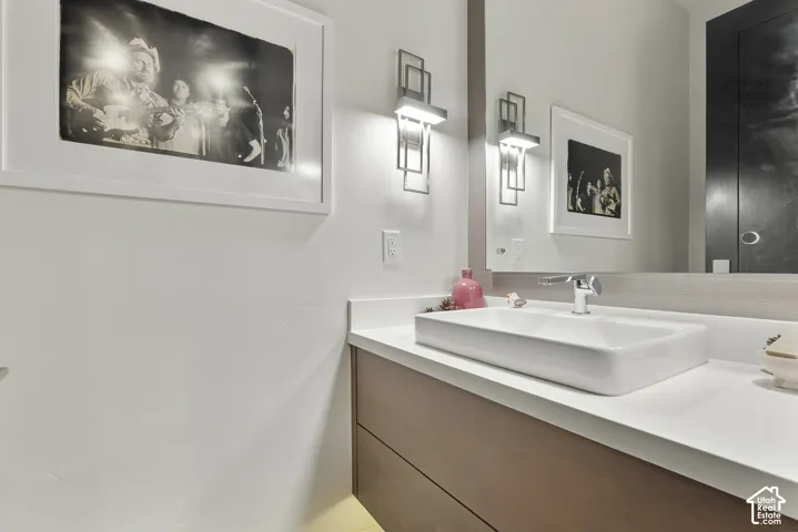 Modern vanity featuring a rectangular vessel sink, polished chrome faucet, white countertop, and wood-finish cabinetry