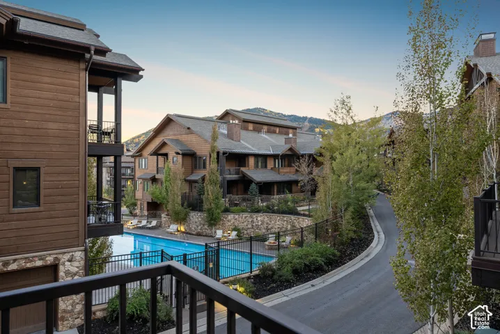 Exterior featuring wood siding, stone accents, multiple balconies, a swimming pool with lounge seating, and an asphalt drive