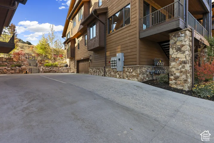 Stone facade with wood siding, integrated garage, and concrete driveway