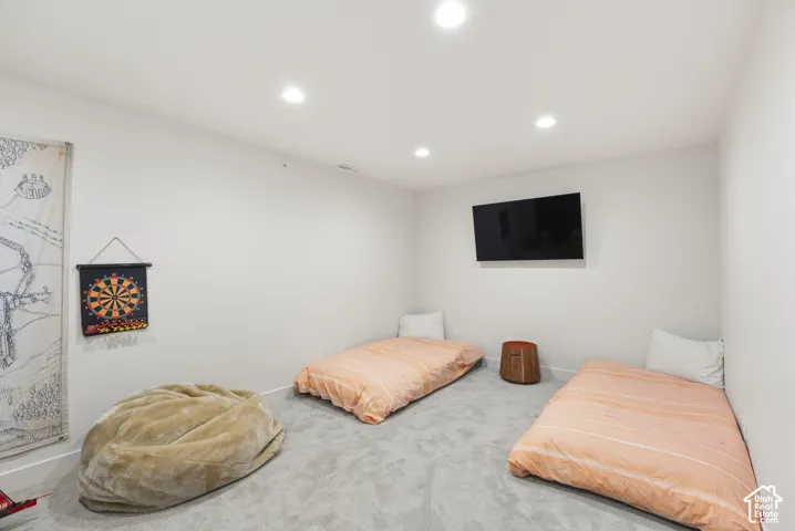 Recessed lighting illuminates this room featuring light gray carpeting and white walls