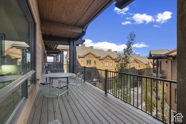 Expansive covered balcony featuring composite decking, wood-plank ceiling, and a black metal railing