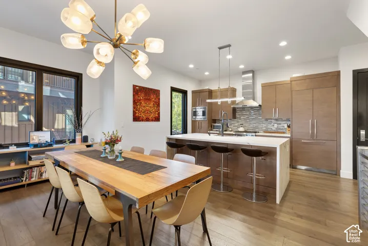 Open-concept living space with wood-finish flooring, a modern chandelier, and large windows