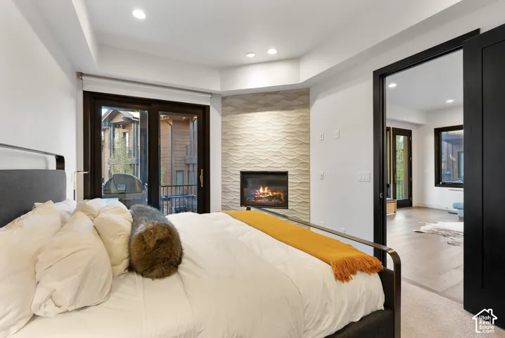 Recessed lighting, contemporary fireplace with wave-patterned tile surround, dark-framed glass patio doors, and dark-framed interior door