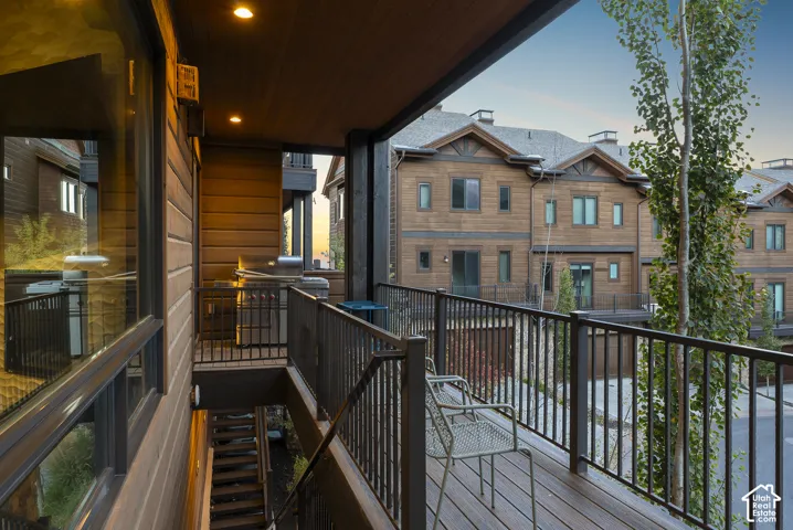 Covered balcony with wood-finish decking, dark metal railings, and recessed lighting