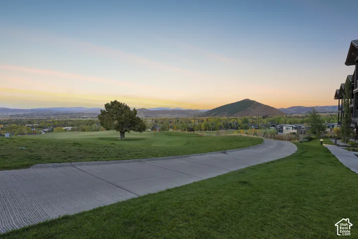 Manicured lawn with a paved pathway, bordered by a golf course and distant mountains