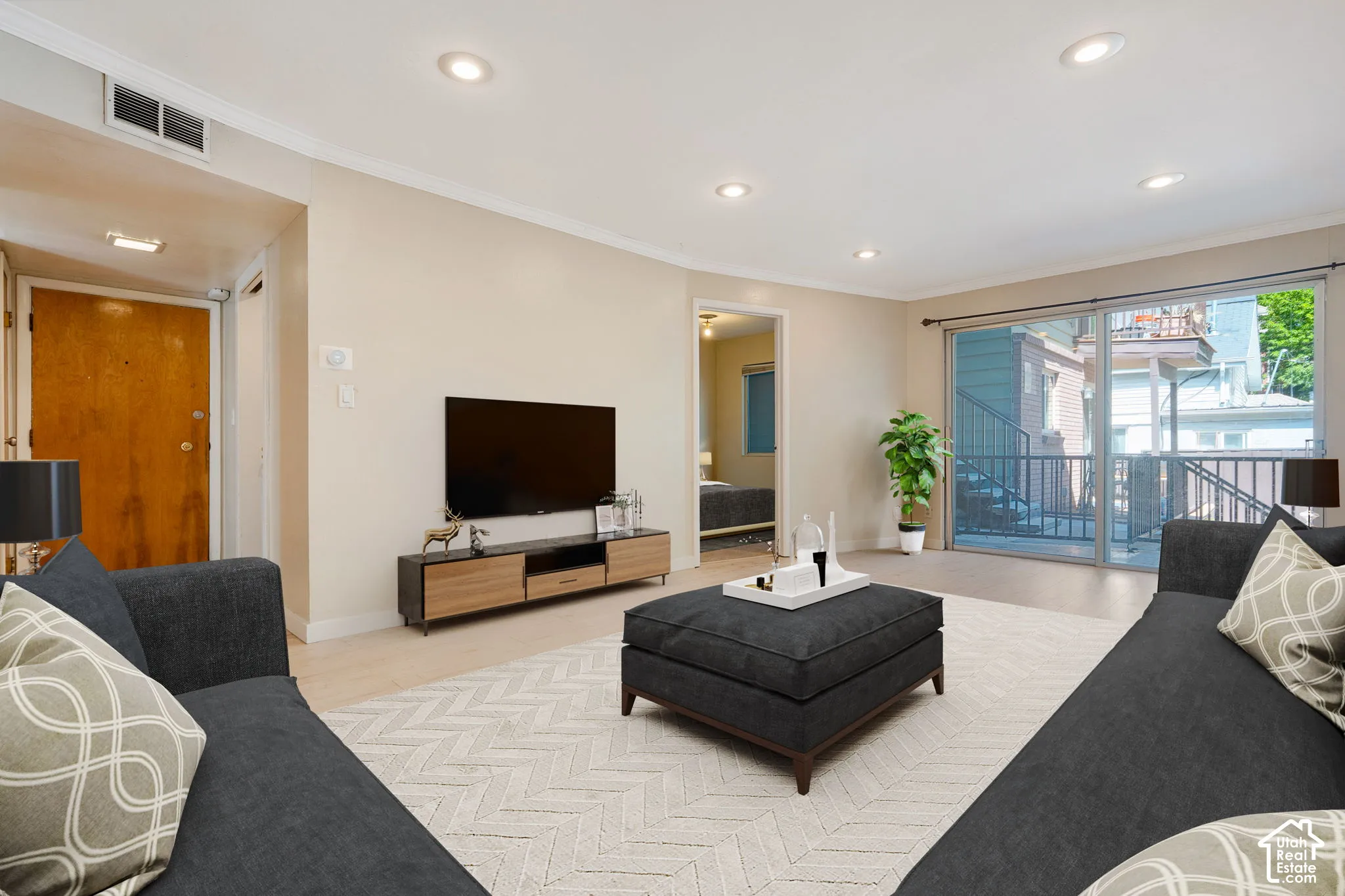 Recessed lighting, light wood-finish flooring, sliding glass door, private balcony with metal railing, and neutral wall tones
