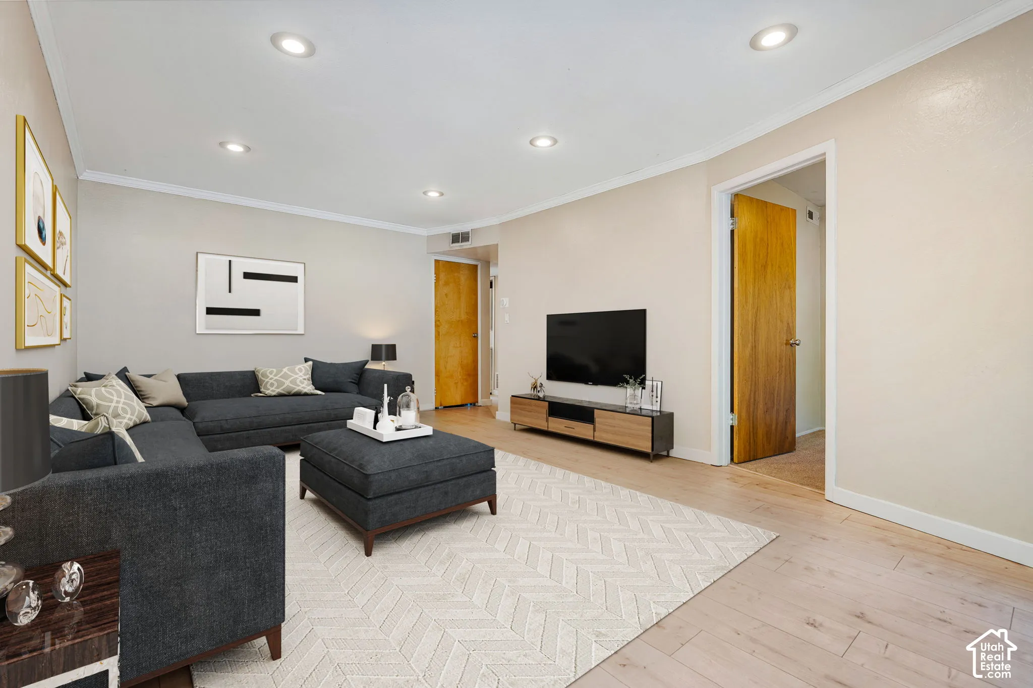 Recessed lighting, light-colored walls, wood-finish flooring, and a flat-panel entertainment console