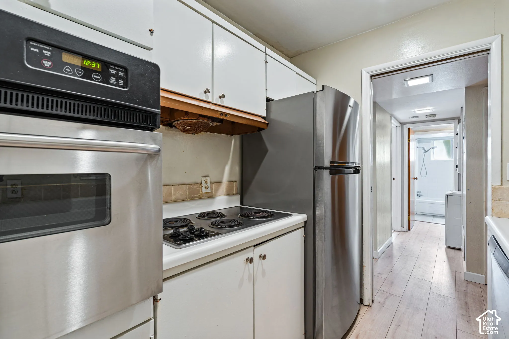 White cabinetry with integrated wall oven and a four-burner electric cooktop