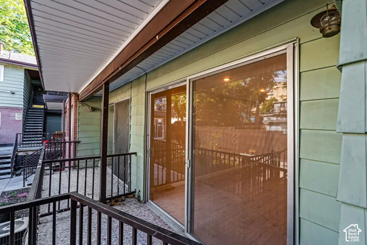 Outdoor patio with black metal railings, sliding glass door entry, and green shingle siding