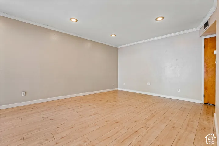Recessed ceiling lighting, crown molding, wood-finish flooring, and a solid-core door